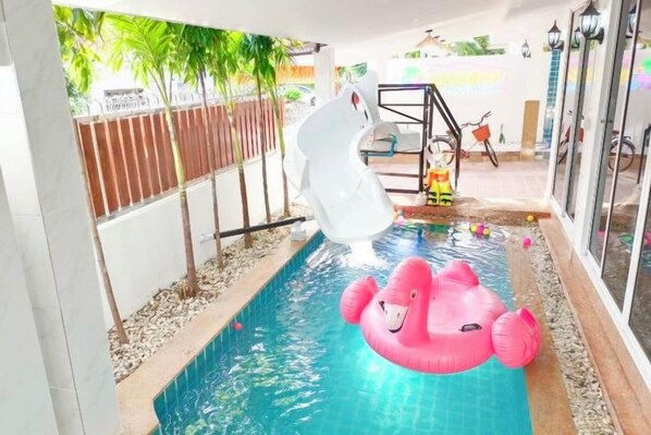 Una piscina con tobogán y juguetes inflables.