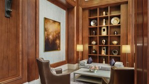 Une pièce avec un mur lambrissé en bois, un grand tableau abstrait, un canapé, une table basse ornée de fleurs et une étagère avec des objets décoratifs.