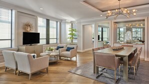 Un salon spacieux doté d’un grand téléviseur à écran plat, de sièges confortables, d’un coin repas avec une table en bois et d’un lustre moderne.