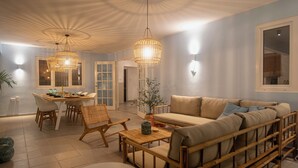 A modern living room with a sofa, dining table, chairs, and a hanging light fixture. - *NEW* Cozy Casa! Tasteful family villa with private pool! (Oranjestad)