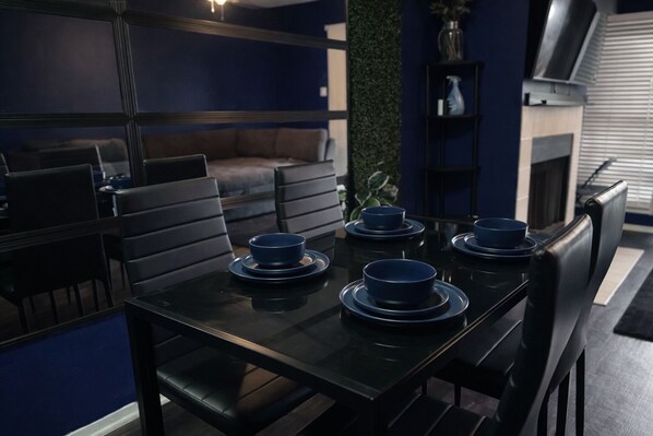 Comedor con una mesa negra dispuesta para cuatro personas, rodeada de sillas negras.