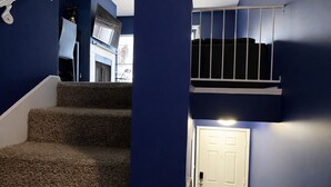 Eine Treppe mit Teppichstufen führt zu einer Empfangshalle mit einer weißen Tür.