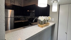 Eine Küche mit Granit Arbeitsplatte, Edelstahlgeräten und einer Vase mit weißen Blumen.