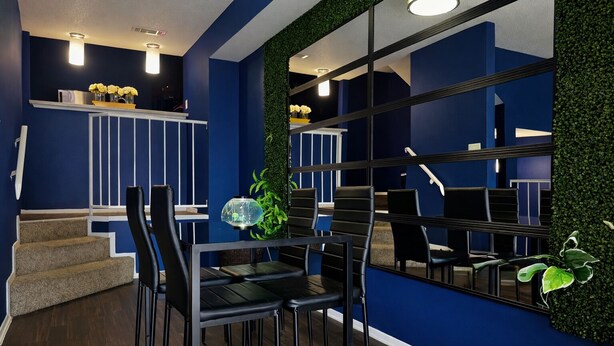 Ein modernes Interieur mit blauer Wand, einer Treppe und einem Essbereich mit schwarzen Stühlen und einem Tisch.