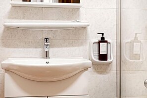A bathroom with a white sink, a soap dispenser, and a glass shower enclosure. - Hotel Domus Rome (Rome)