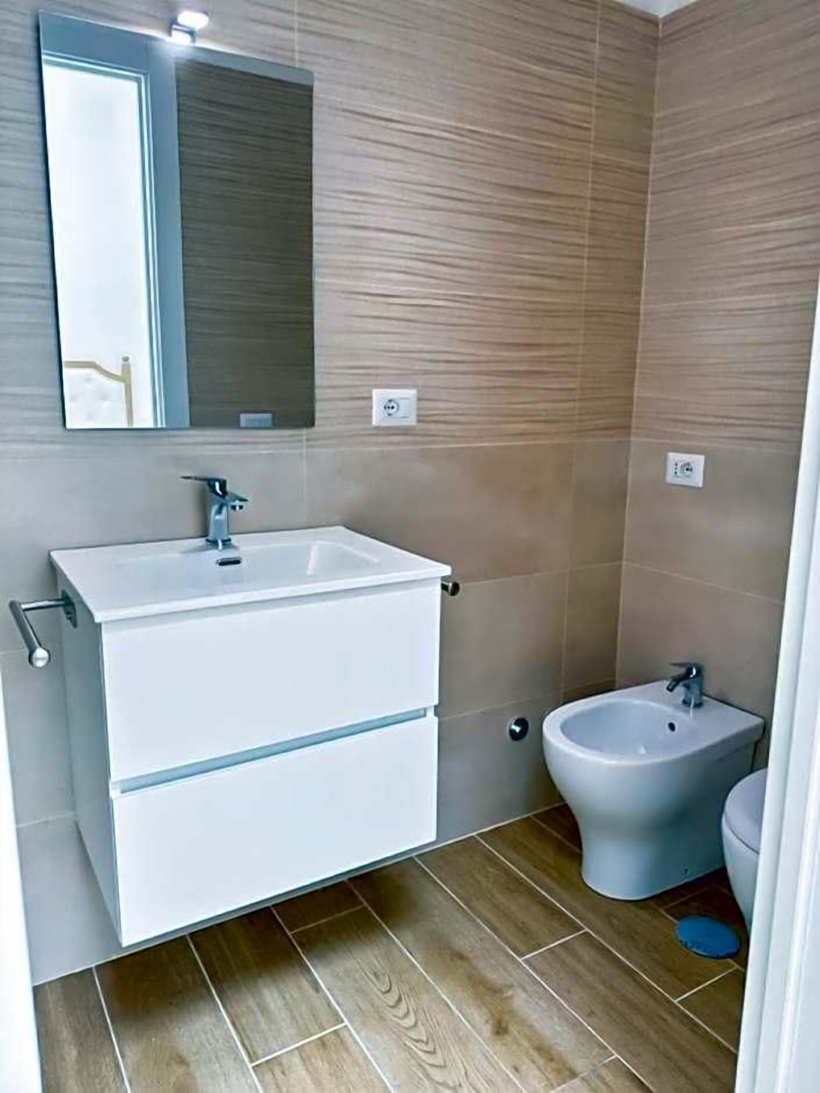 A bathroom with a white sink, a bidet, and a mirror.