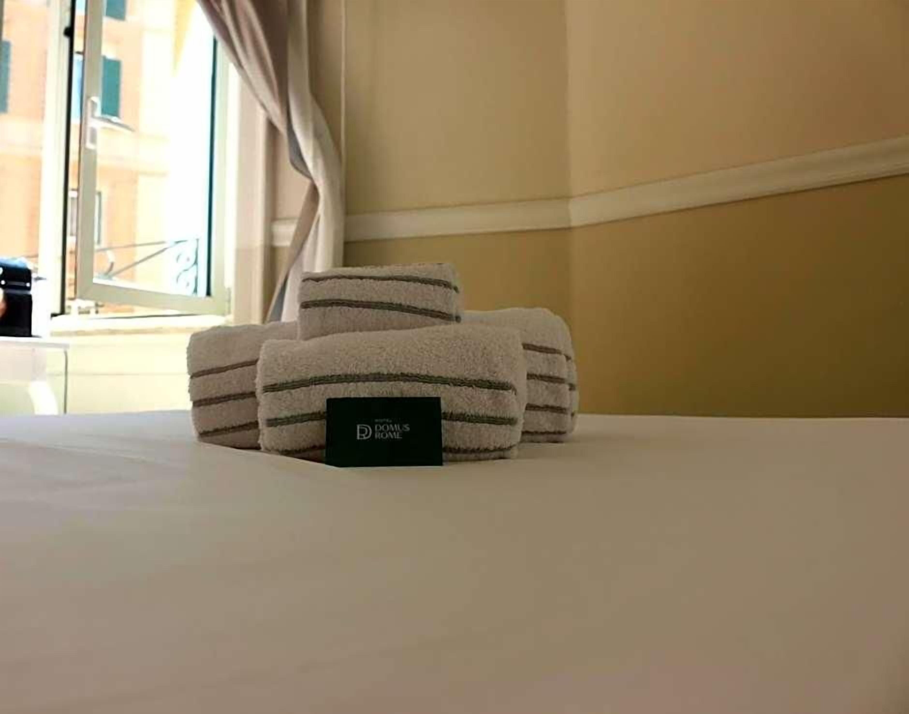 A neatly made bed with folded towels and a black card on the bed.