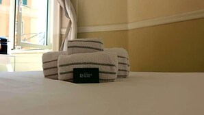 A neatly made bed with folded towels and a black card on the bed. - Hotel Domus Rome (Rome)