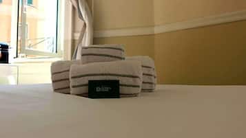 A neatly made bed with folded towels and a black card on the bed.