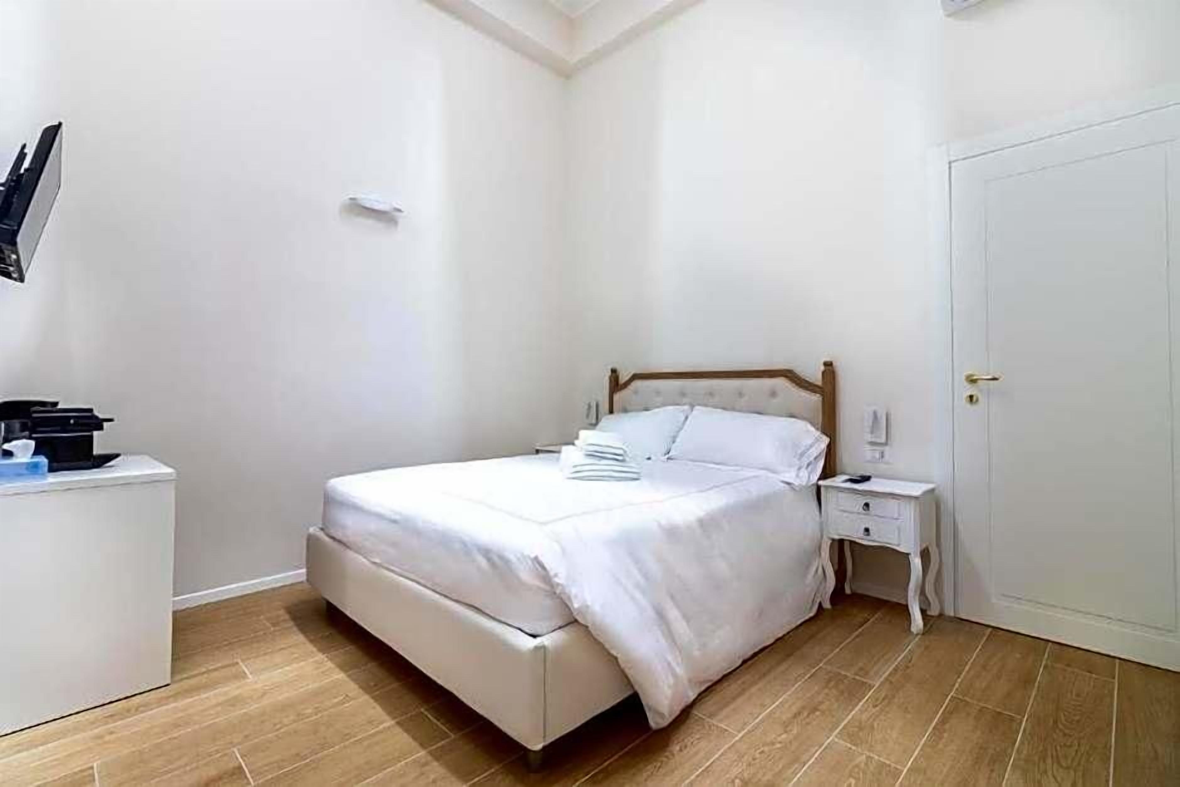 A bedroom with a bed, bedside tables, a wardrobe, and a door.