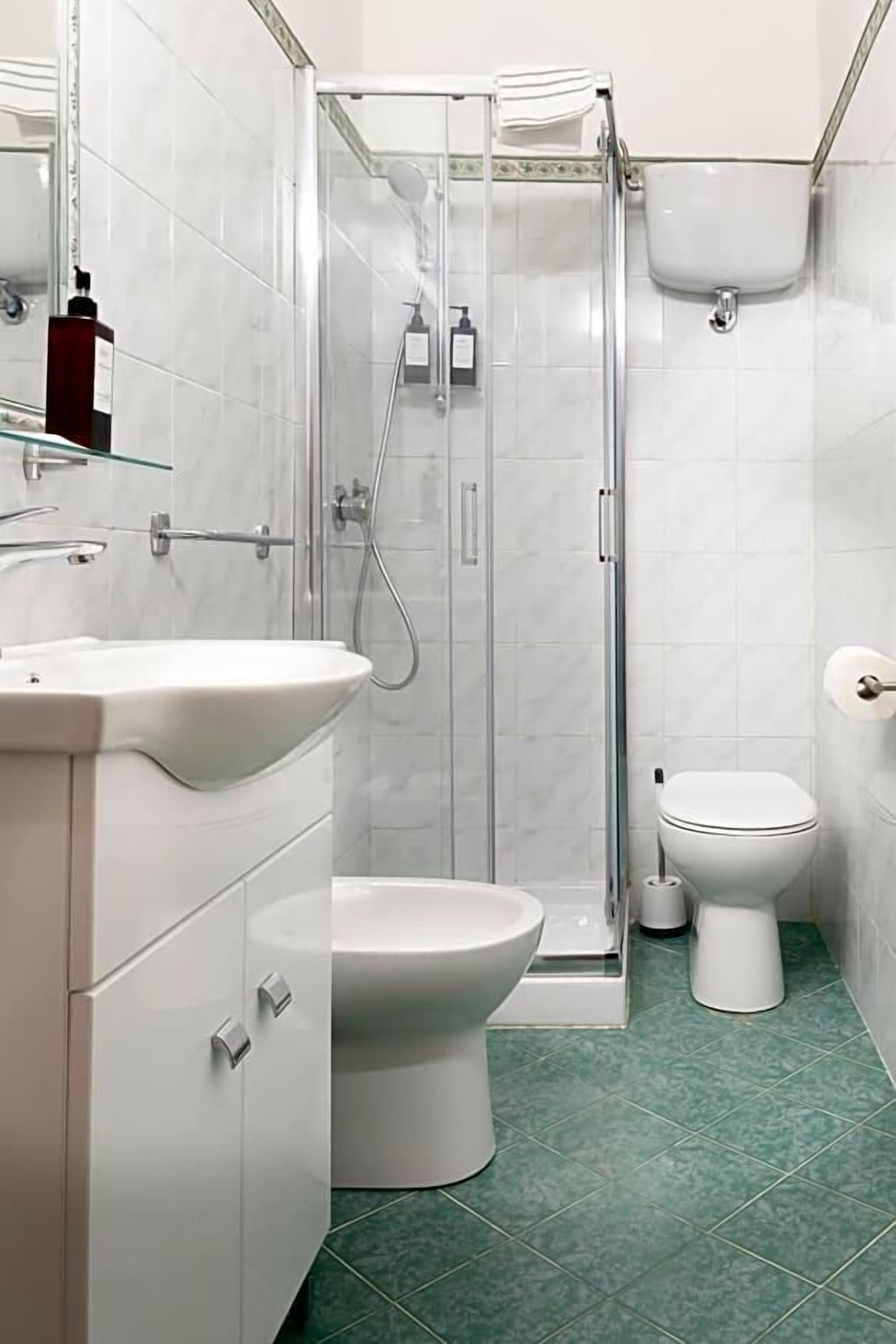 A modern bathroom with a glass-enclosed shower, a white sink, and a toilet.