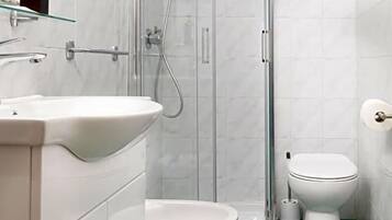 A modern bathroom with a glass-enclosed shower, a white sink, and a toilet.