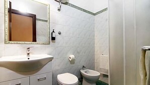 A bathroom with a sink, toilet, bidet, and a mirror with a decorative frame. - Hotel Domus Rome (Rome)