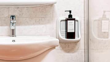 A bathroom with a white sink, a hand soap dispenser, and a soap dispenser on the wall.