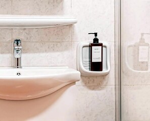 A bathroom with a white sink, a hand soap dispenser, and a soap dispenser on the wall. - Hotel Domus Rome (Rome)