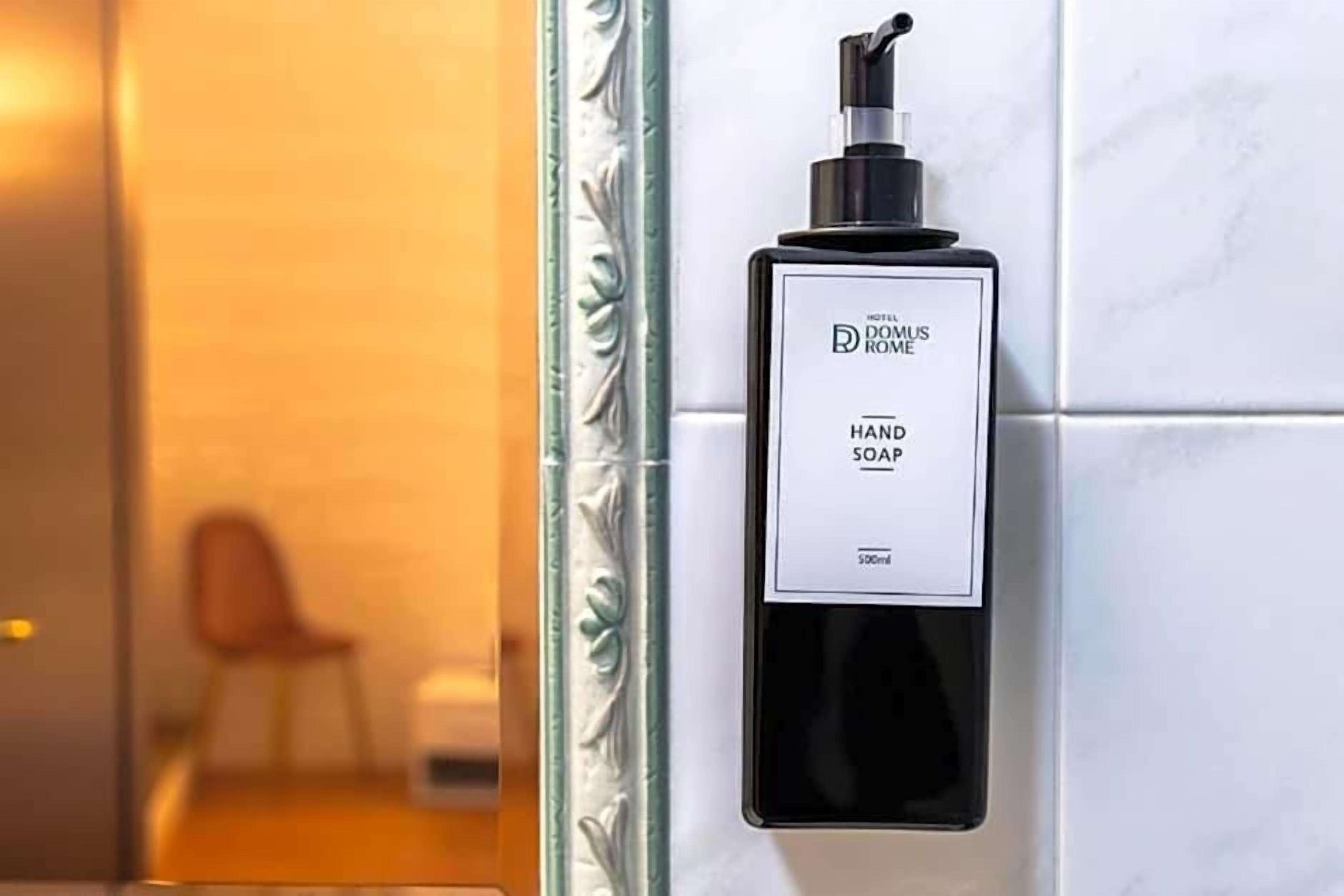 Dispensador de jabón para manos en una pared de azulejos blancos.