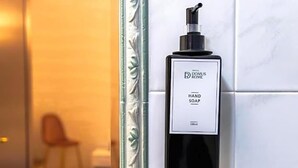 A hand soap dispenser on a white tiled wall. - Hotel Domus Rome (Rome)