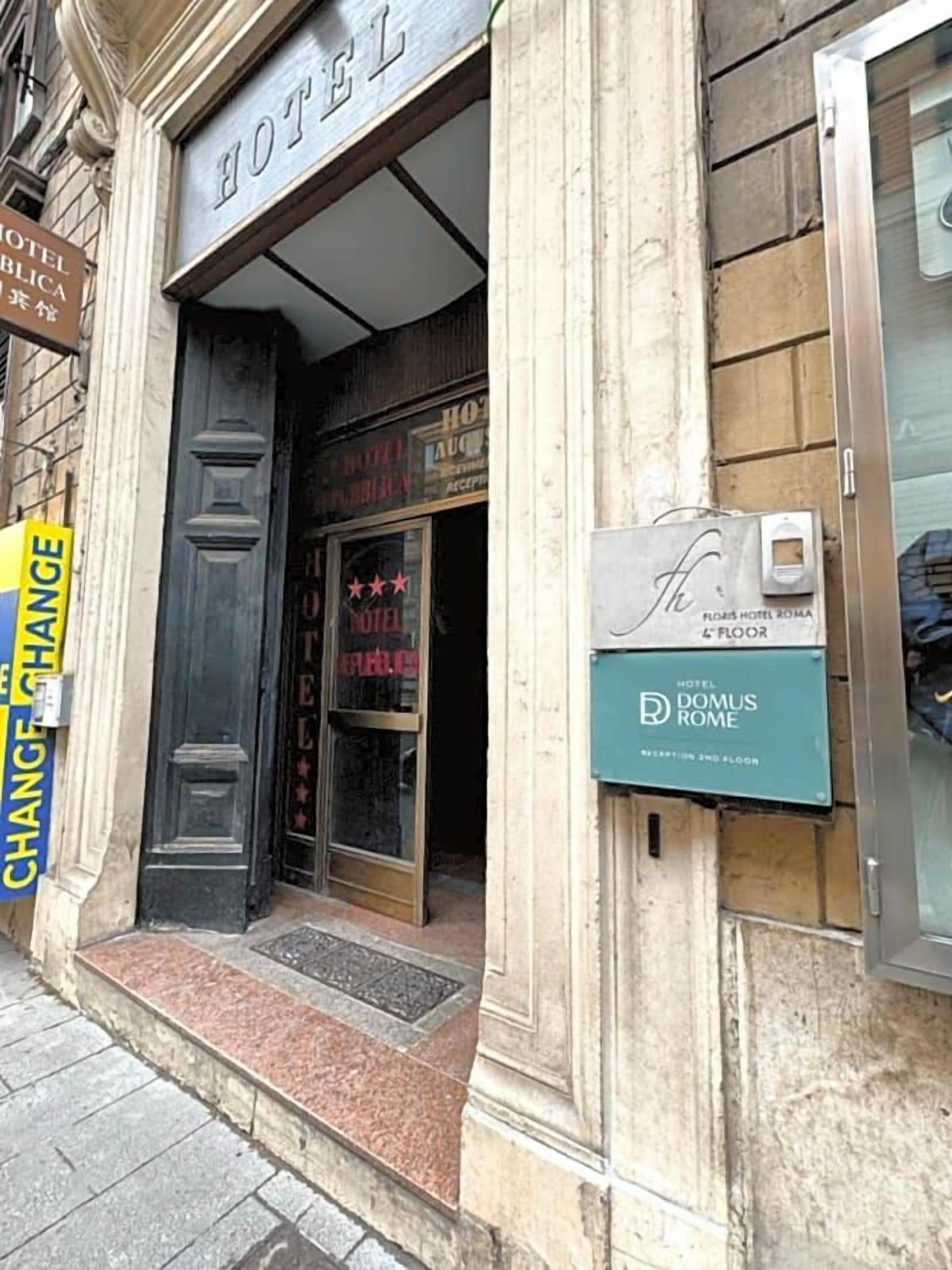 Entrada de un hotel con un letrero que dice "HOTEL DOMUS ROME" y un letrero de "CAMBIO DE HABITACIÓN".