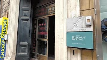 Entrada de un hotel con un letrero que dice "HOTEL DOMUS ROME" y un letrero de "CAMBIO DE HABITACIÓN".