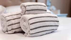Three rolled towels with dark stripes on a bed. - Hotel Domus Rome (Rome)