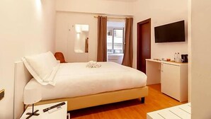 A hotel room with a bed, bedside table, lamp, TV, and a small kitchenette. - Hotel Domus Rome (Rome)