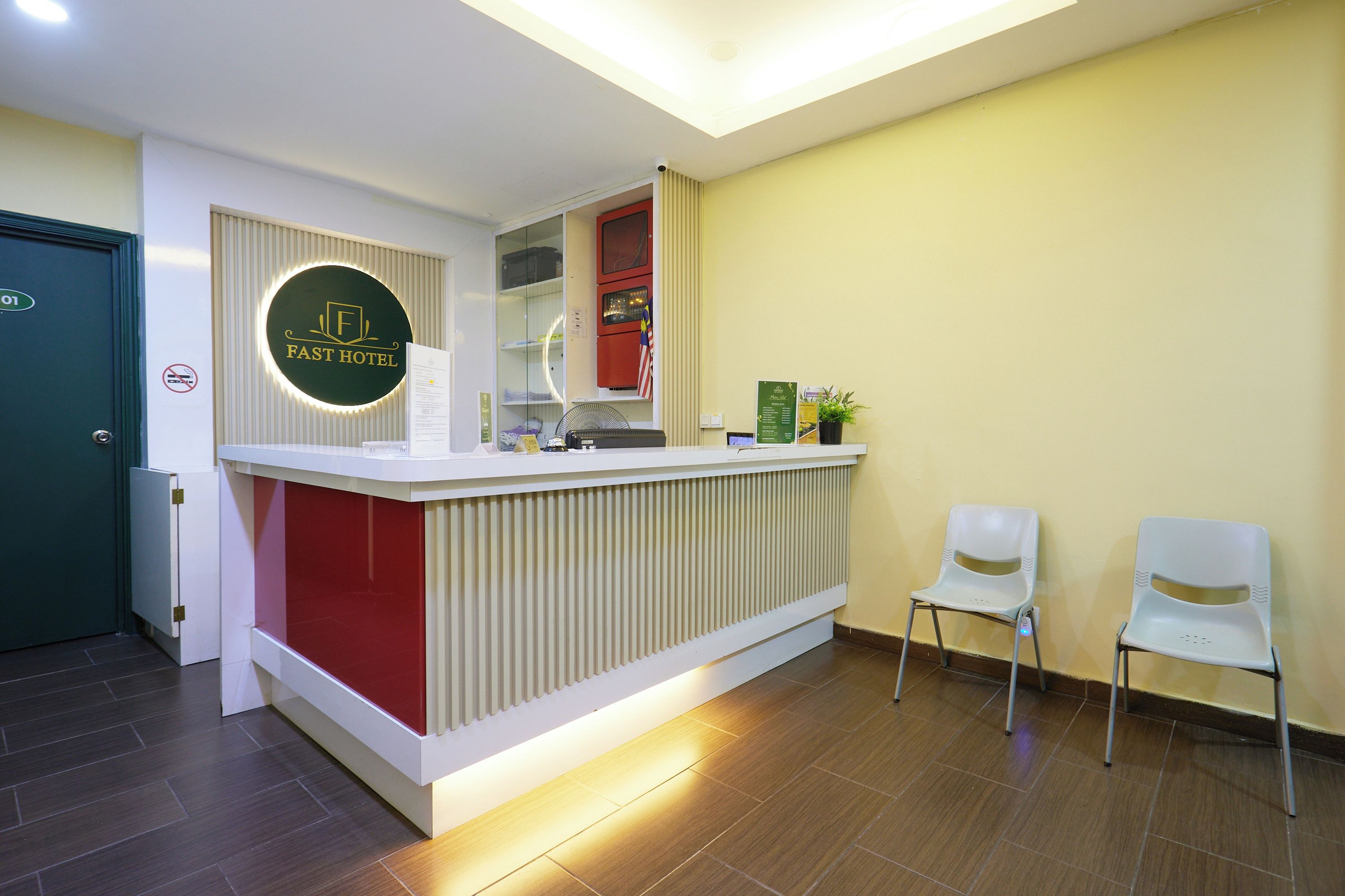 A reception desk with a circular logo, a red accent wall, and two white chairs.