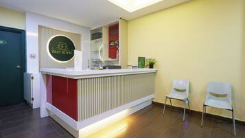 A reception desk with a circular logo, a red accent wall, and two white chairs.