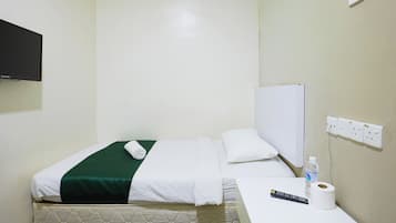 Habitación de hotel con una cama, una mesita de noche con un control remoto, un rollo de papel higiénico y una botella de agua.