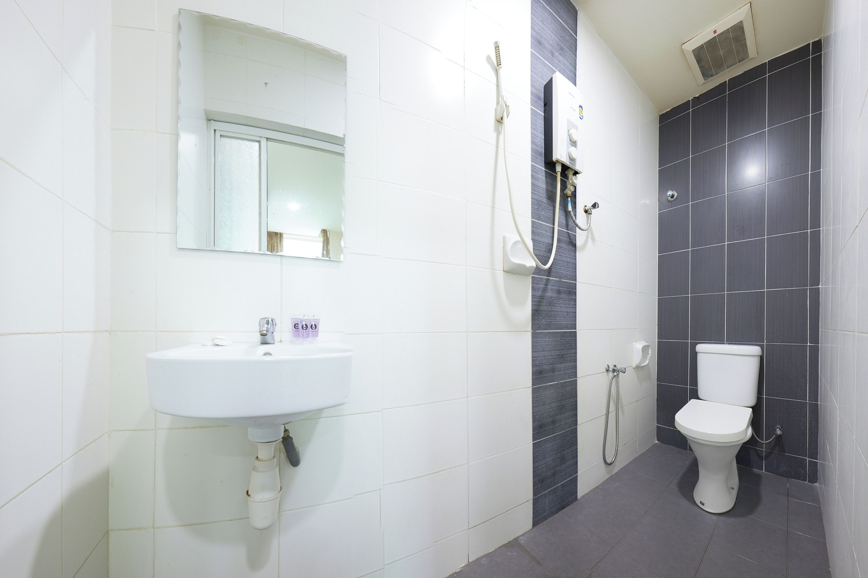 A bathroom with a white sink, a mirror, a shower, and a toilet.