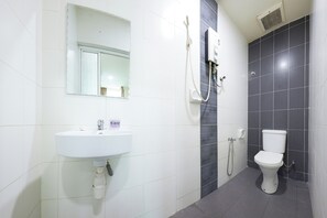 Une salle de bain avec un lavabo blanc, un miroir, une douche et des toilettes.