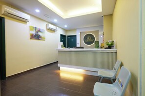 Ein Hotel-Empfangsbereich mit einer Rezeption, einem Wartebereich und einem an der Wand befestigten Schild.