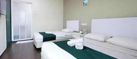 A hotel room with two beds, a green bed runner, white bedding, a nightstand with a lamp, and a painting on the wall.