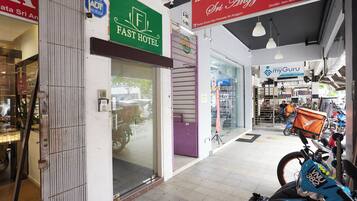 A commercial area with a Fast Hotel entrance, a sign for Kedai Emas Sri Anggun, and a motorcycle parked outside.