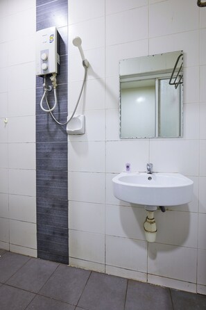 Un baño con lavamanos blanco, un espejo y cabina de ducha.