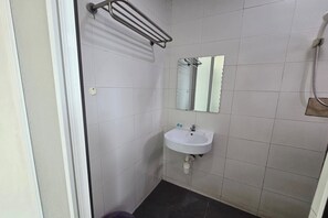 Ein kleines Badezimmer mit weiß gefliesten Wänden, einem weißen Waschbecken, einem Spiegel und einem Handtuchhalter.