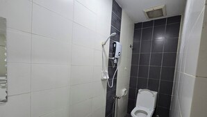 A bathroom with white and black tiles, a toilet, and a shower unit. - Fast Hotel Sri Gombak By Zuzu (Batu Caves)