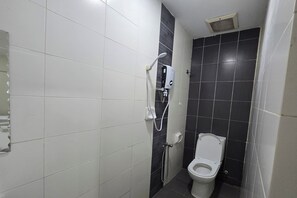 A bathroom with white and black tiles, a toilet, and a shower unit. - Fast Hotel Sri Gombak By Zuzu (Batu Caves)