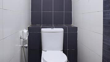 Un baño pequeño y moderno con inodoro, ducha y secamanos.