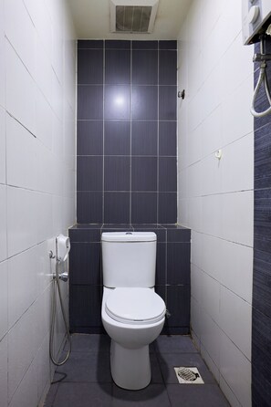 A small, modern bathroom with a toilet, a shower, and a hand dryer. - Fast Hotel Sri Gombak By Zuzu (Batu Caves)