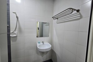 Une petite salle de bain avec un lavabo blanc, un miroir et une douche.