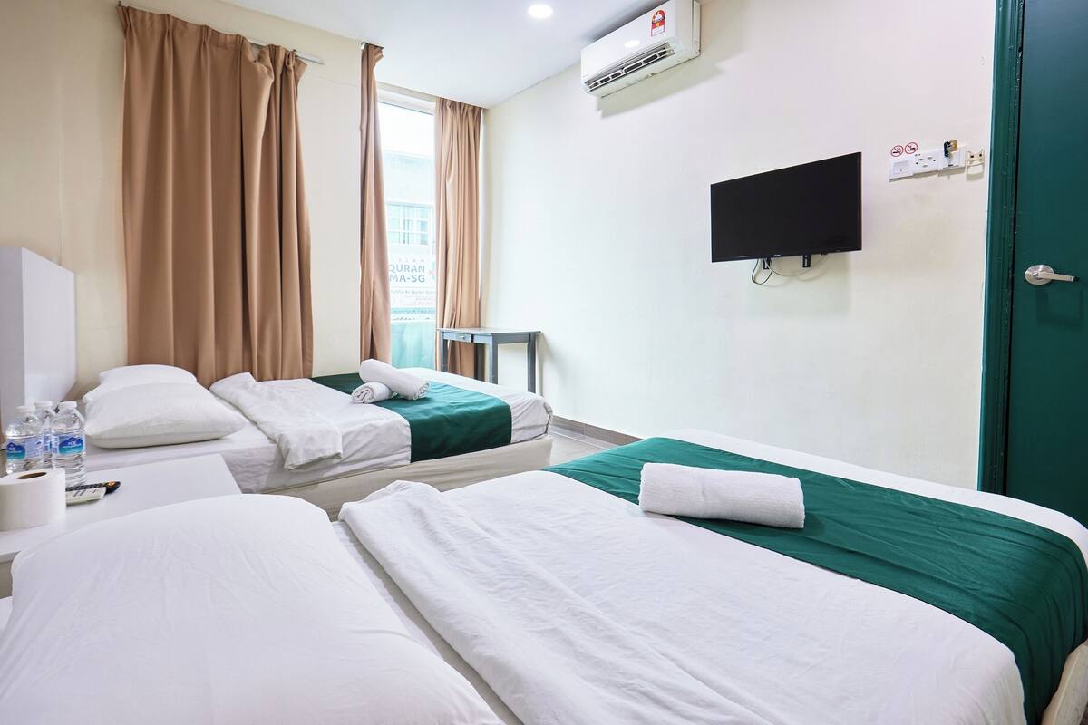Habitació d'hotel amb dos llits, televisió, aire condicionat i finestra amb cortines.