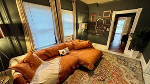 Una habitación con un sofá grande, un tapete estampado y una pared adornada con cuadros.
