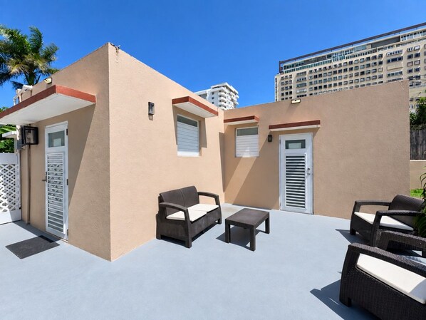A rooftop patio with outdoor furniture, including a sofa and a table, and a door with a window.
