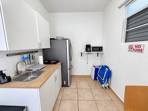 A compact kitchen with a sink, refrigerator, microwave, and a 'NO FUME' sign.