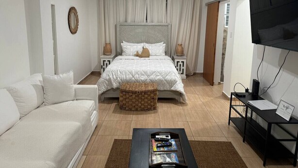 A bedroom with a bed, a sofa, a coffee table, and a TV.