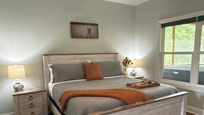 A bedroom with a wooden bed, a nightstand, a ceiling fan, a window, and a framed picture on the wall. - Charming 2-bedroom house-Walk to Helen-Your Perfect Getaway (Helen)