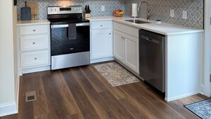 A modern kitchen with white cabinetry, stainless steel appliances, and a patterned backsplash. - Charming 2-bedroom house-Walk to Helen-Your Perfect Getaway (Helen)