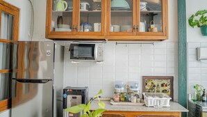 A kitchen with wooden cabinets, a microwave, a toaster, and a refrigerator. - Omah Gerjen 29 By Zuzu (Yogyakarta)