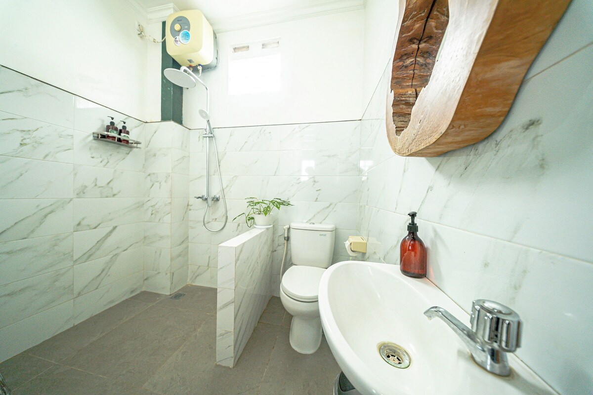 A bathroom with a toilet, sink, shower, and marble tiles.