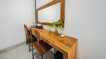 A wooden desk with a mirror, a chair, a plant, and a tissue box.